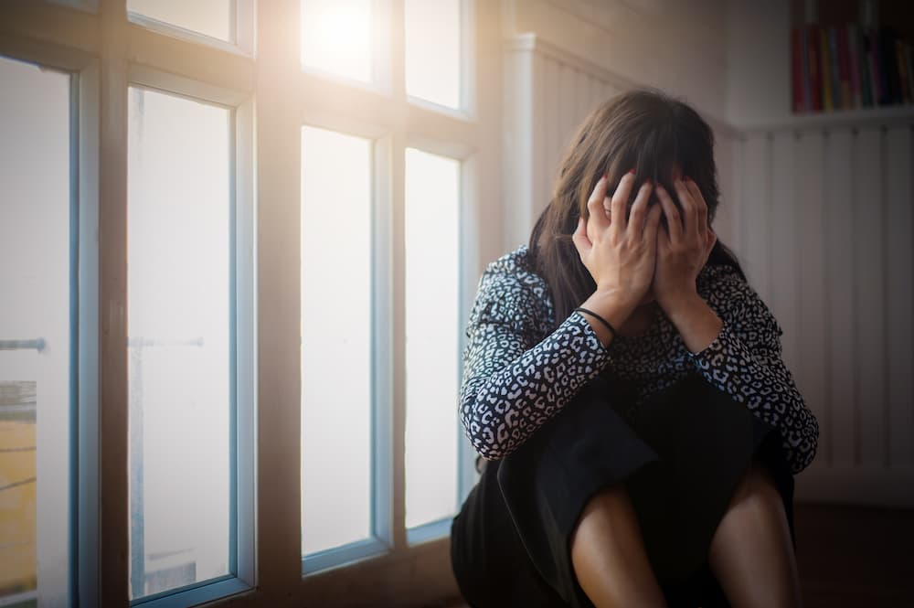 顔に手を当てて悲しむ女性